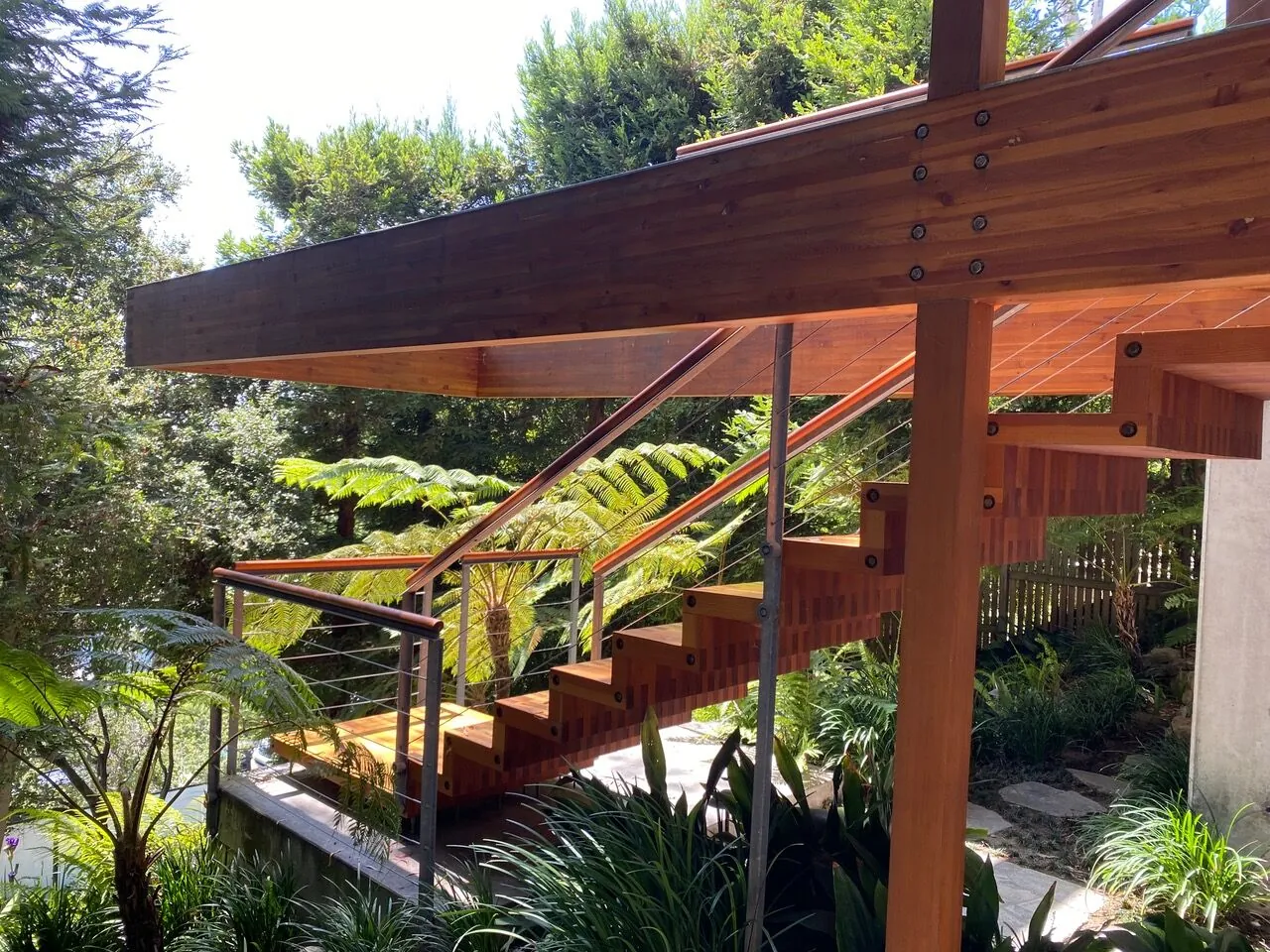 Timber and steel outdoor staircase set among lush tropical landscaping in Pacific Palisades