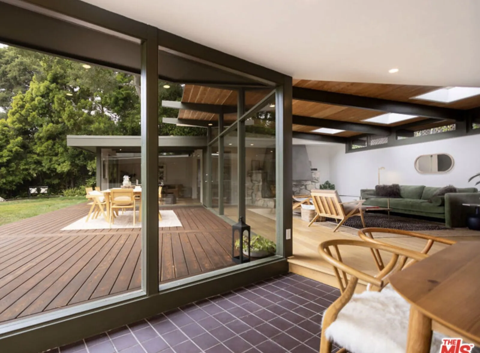 Mid-century glass-walled home with expansive deck overlooking mature oaks in Rustic Canyon